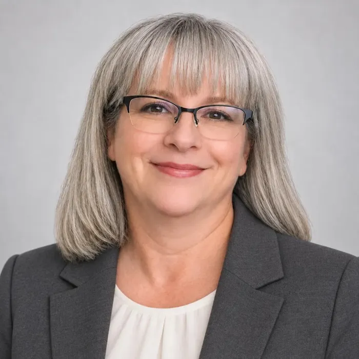 Traci Baker, smiling, gray hair and glasses